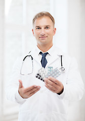 Image showing young male doctor with packs of pills