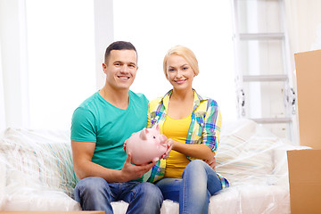 Image showing smiling couple with piggybank in new home