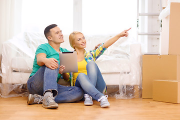 Image showing smiling couple with tablet pc in new home