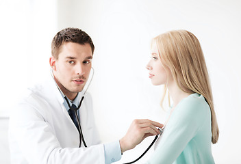 Image showing doctor with stethoscope listening to the patient