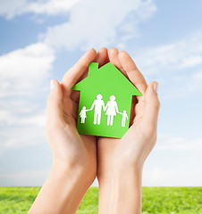 Image showing hands holding green house with family