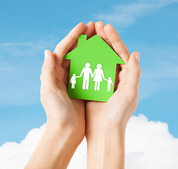 Image showing hands holding green house with family