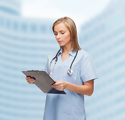 Image showing smiling female doctor or nurse with clipboard