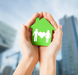 Image showing hands holding green house with family