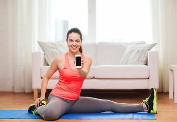 Image showing smiling teenage girl streching on floor at home