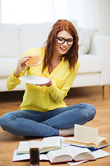 Image showing student eating hamburger and doing homework