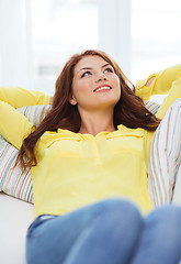 Image showing smiling young woman lying on sofa at home