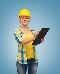 Image showing smiling woman in helmet with clipboard