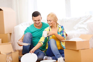 Image showing smiling couple unpaking boxes with kitchenware