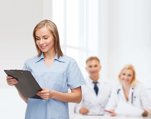 Image showing smiling female doctor or nurse with clipboard