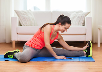 Image showing smiling teenage girl streching on floor at home