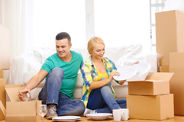 Image showing smiling couple unpaking boxes with kitchenware