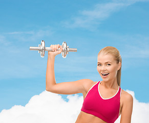 Image showing smiling woman with heavy steel dumbbell