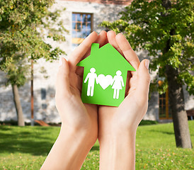 Image showing hands holding green house with family