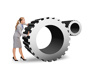 Image showing busy businesswoman pushing cogwheel