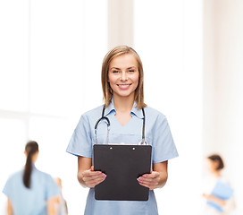 Image showing smiling female doctor or nurse with clipboard