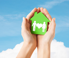 Image showing hands holding green house with family