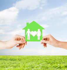 Image showing hands holding green house with family