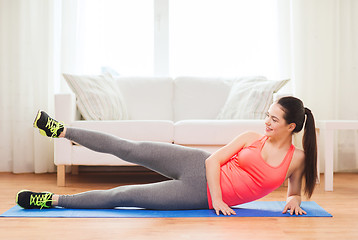 Image showing smiling teenage girl doing exercise for legs