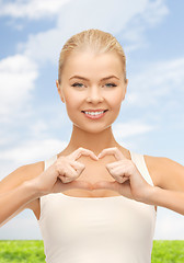 Image showing smiling woman showing heart shape gesture