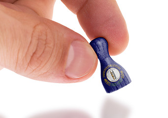 Image showing Hand holding wooden pawn, flag painting, selective focus