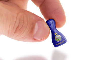 Image showing Hand holding wooden pawn, flag painting, selective focus