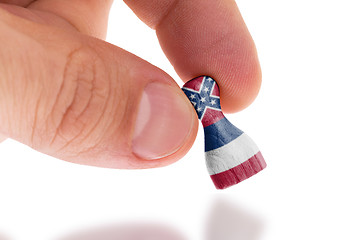 Image showing Hand holding wooden pawn, flag painting, selective focus