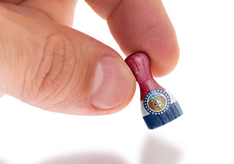 Image showing Hand holding wooden pawn, flag painting, selective focus