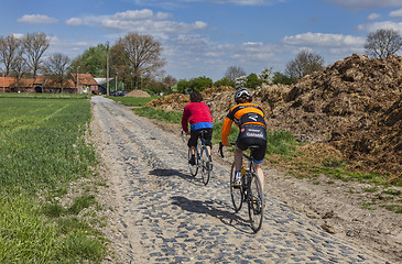 Image showing Amateur Cyclists on a Cobblestone Road