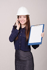 Image showing Builder in helmet talking but phone with a folder hands