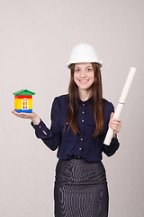 Image showing Girl stands with a house builder and drawing in hands