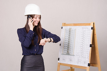 Image showing Girl in helmet talking phone and looking at his watch