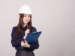 Image showing Builder in helmet writes pencil folder