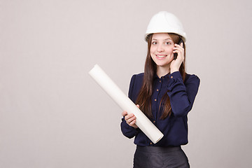 Image showing Designer talking on phone with blueprints in hand