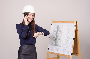 Image showing Architect girl talking on phone and looking at his watch