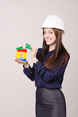 Image showing Construction worker stands with a house in the hands of