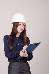 Image showing Girl a helmet writes in pencil folder