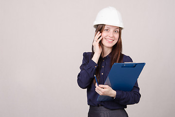 Image showing woman in hard hat talking to a customer on phone