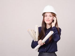 Image showing Architect talking on phone with blueprints in hand