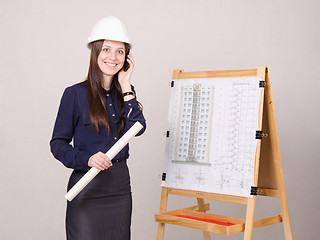 Image showing Girl a helmet talking on phone with drawing in hands