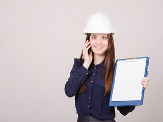 Image showing Girl talking on the phone with a folder in hands