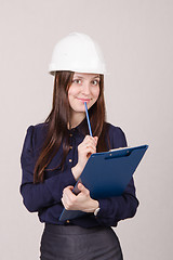 Image showing Beautiful girl a helmet writes in pencil folder