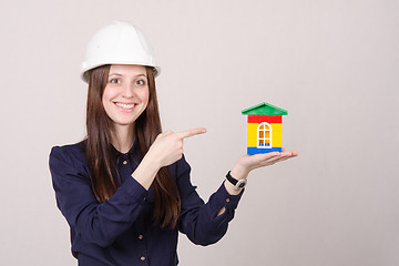Image showing Beautiful girl in helmet points to house layout
