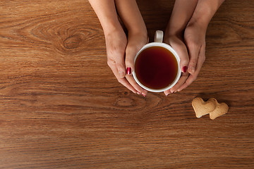 Image showing Womans and mens hands holding hot cup of tea