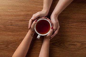 Image showing woman holding hot cup of tea with cookies