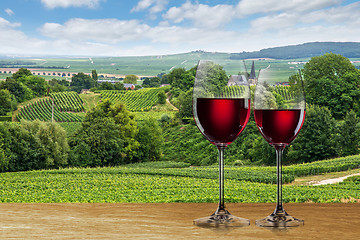 Image showing Glass of red wine against vineyard