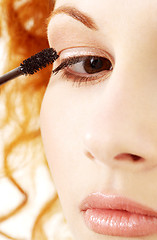 Image showing lovely redhead applying black mascara
