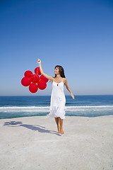 Image showing Beautiful girl running with red ballons