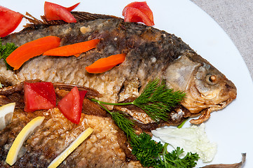 Image showing Fresh crucian river fish fried in lemon juice and fresh herbs.