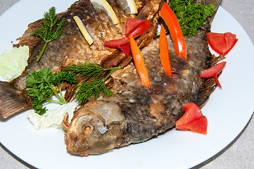 Image showing Fresh crucian river fish fried in lemon juice and fresh herbs.